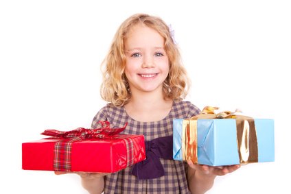 Ein lachendes Kind mit zwei Geschenken in der Hand.