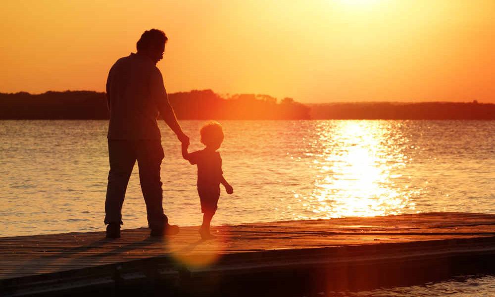 Vater spaziert mit seinem Sohn am Strand