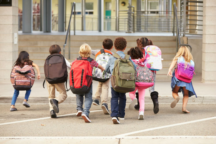 Kinder, die mit Schulranzen zur Schule laufen