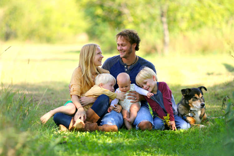 Glückliche Familie sitz mit ihrem Haustier im Grünen