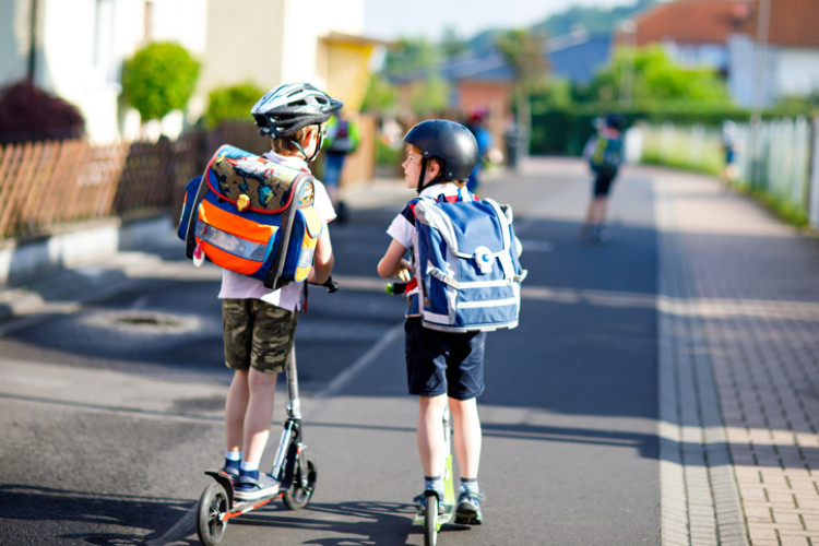 Zwei Kinder auf einem Roller im Straßenverkehr