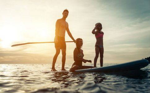 Junge Familie beim Stand Up Paddling auf einem See
