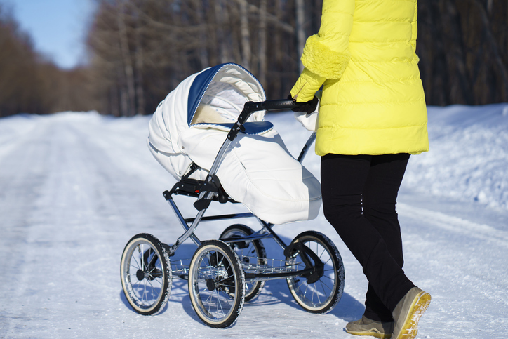 Mutter mit Kinderwagen im Schnee